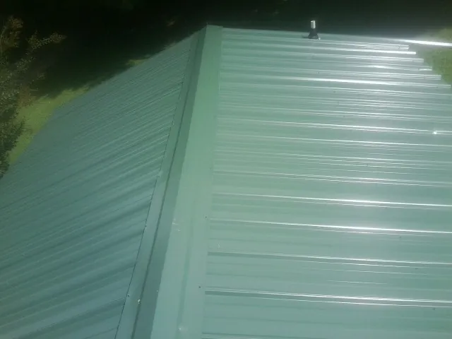 New green metal panels meeting at the ridge of a roof — Flat Roof Repair work by our crew in Brookshire