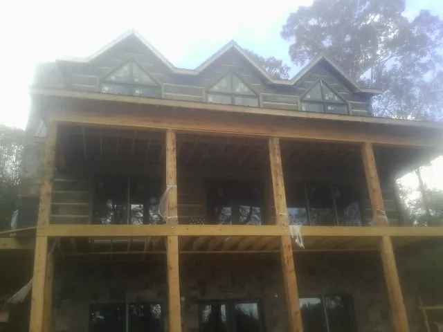 Dormers and porch framing on a large log home under construction — Roof Coating work by our crew in Brookshire