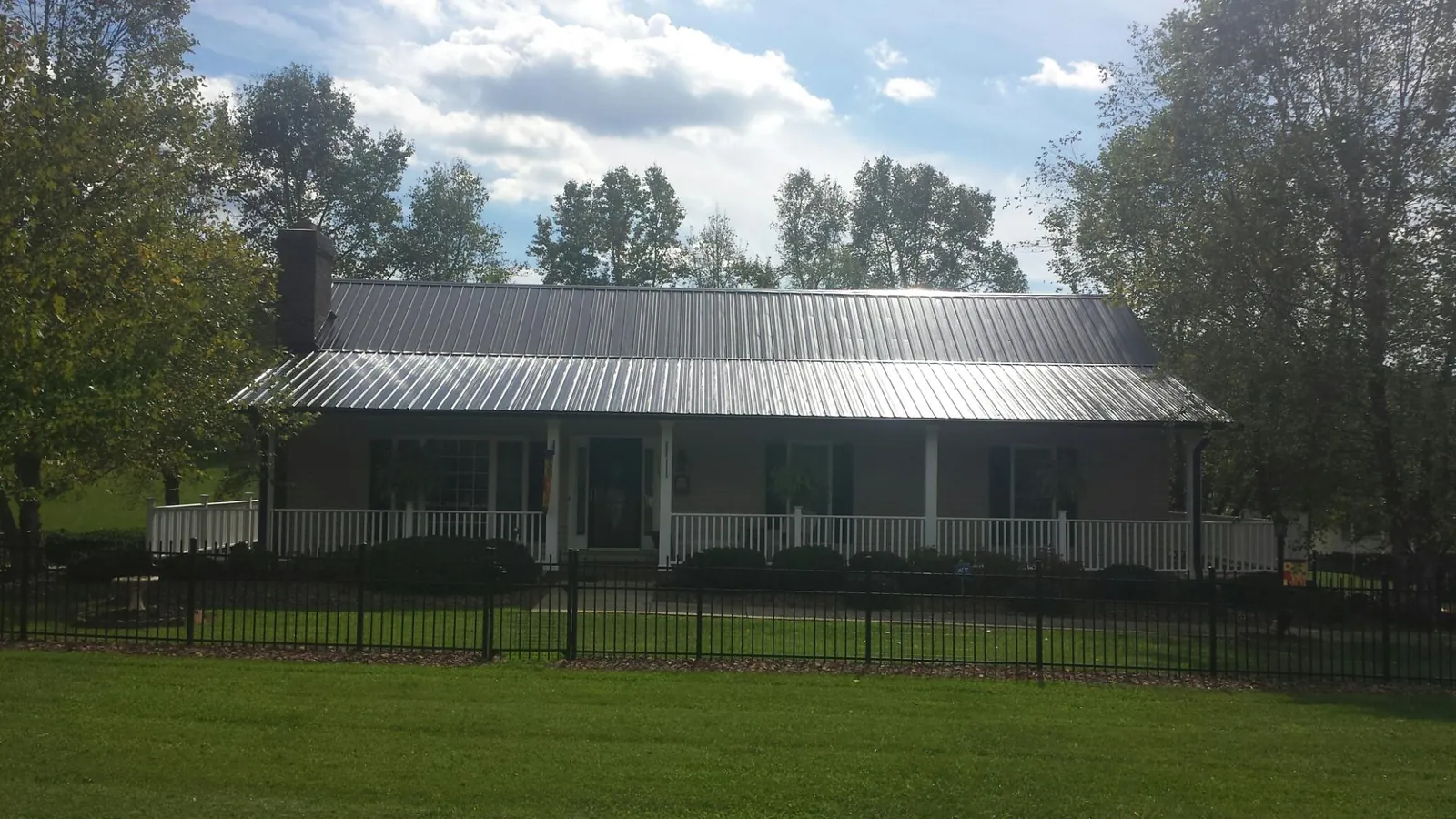 Gray metal roof on a brick ranch with a full width front porch — Gutter Guard Installation work by our crew in Brookshire