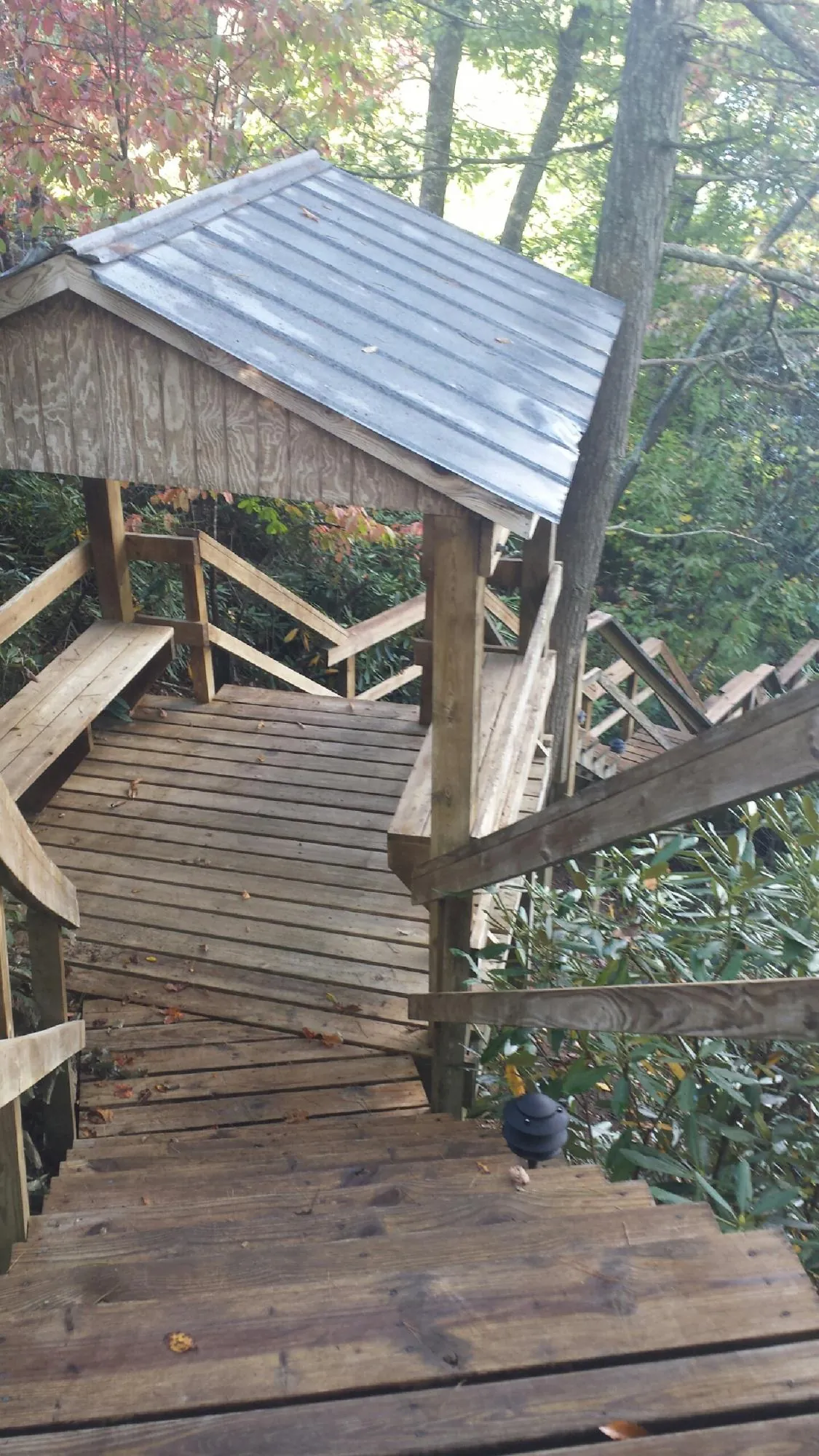 Metal roofed shelter over wooden steps on a wooded walkway — Skylight Repair & Installation work by our crew in Brookshire