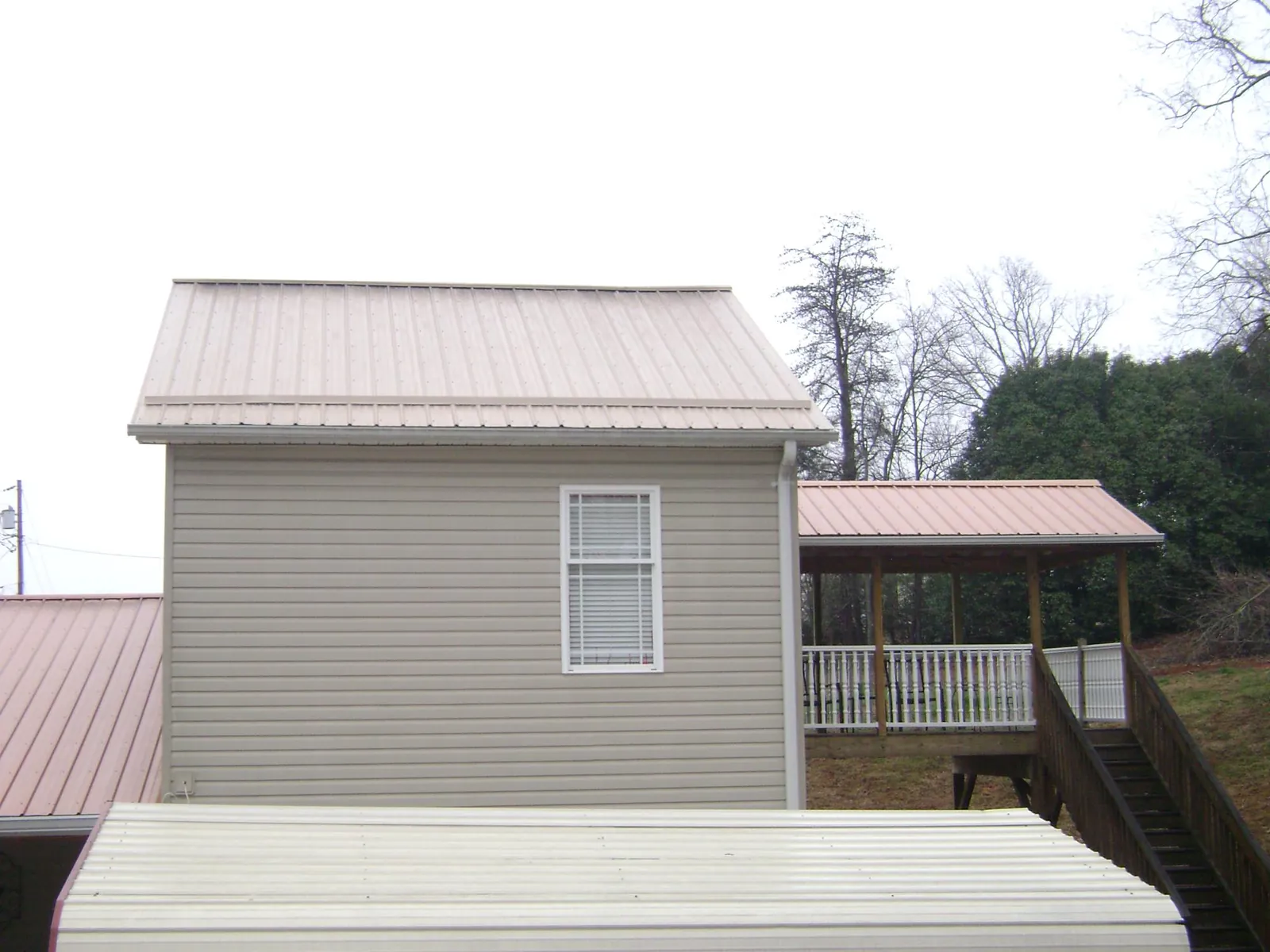 Tan metal roofs on a two story addition and attached porch, from a Roof Replacement job in Brookshire