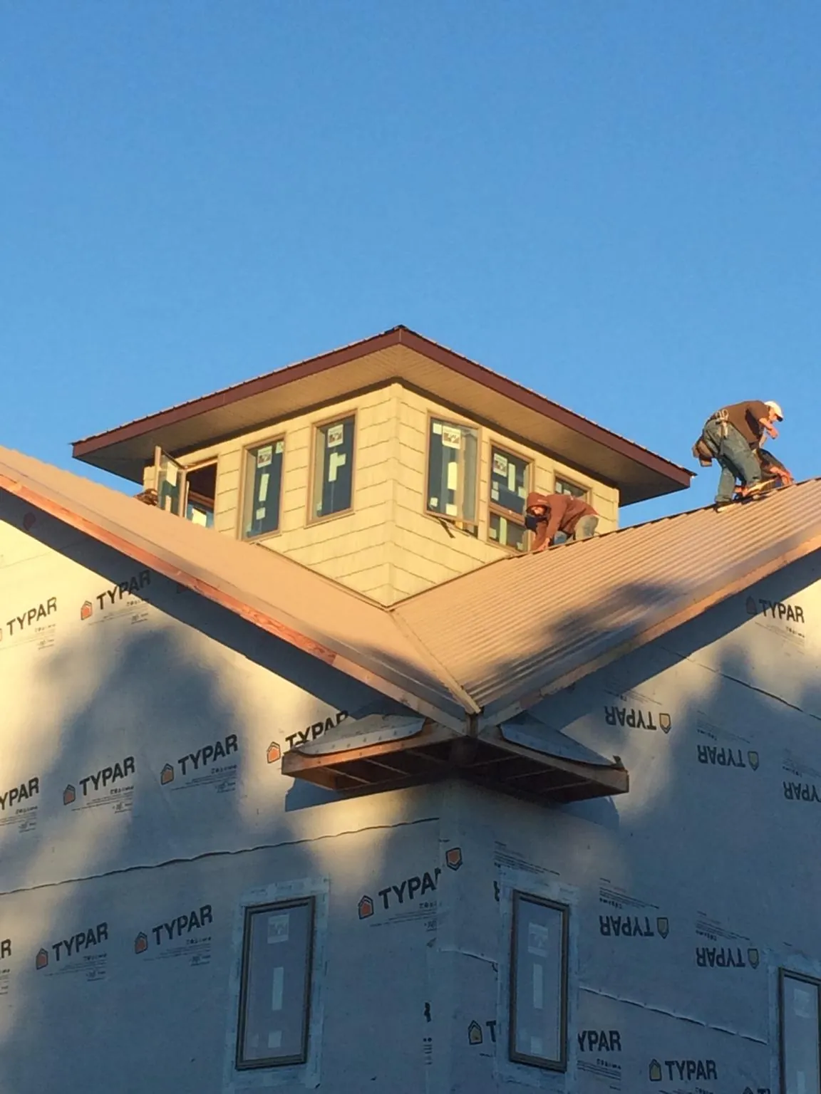 Roofers working around a rooftop cupola on a new metal roof at sunset — Roof Waterproofing in Brookshire by Roofing Brothers